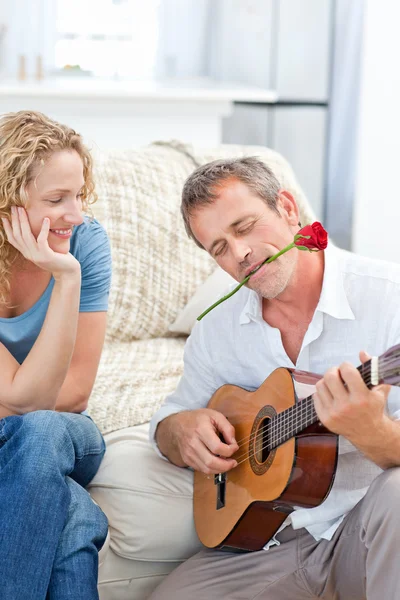 Romantyczny mężczyzna gra na gitarze dla jej żony w domu — Zdjęcie stockowe