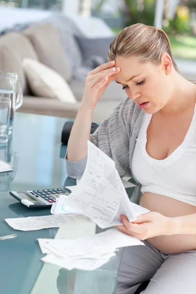 Беспокойная беременная женщина рассчитывает домашние счета — стоковое фото