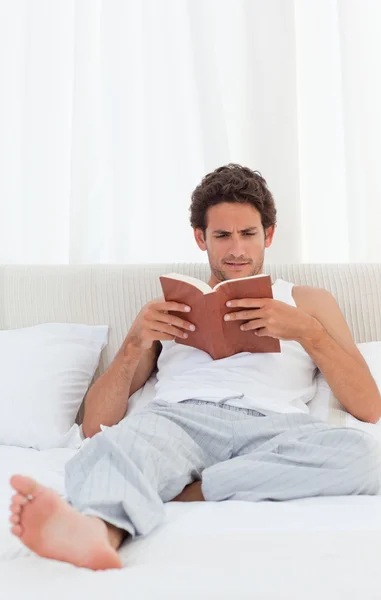 Homme lisant un livre sur son lit — Photo