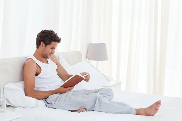 Άνθρωπος, διαβάζοντας ένα βιβλίο στο κρεβάτι του — Φωτογραφία Αρχείου