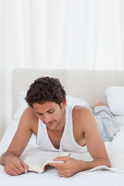 Homem lendo um livro em sua cama — Fotografia de Stock