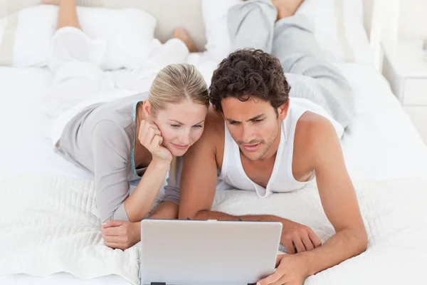 Imádnivaló pár nézi a laptop az ágyon — Stock Fotó