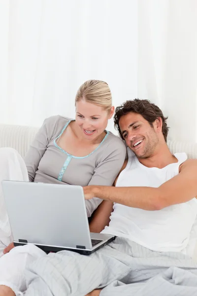 Adorable couple regardant leur ordinateur portable sur le lit — Photo