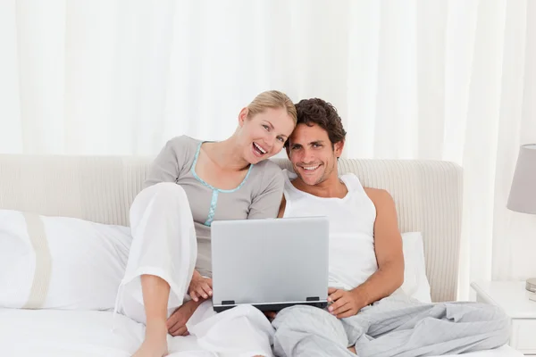 Αξιολάτρευτο ζευγάρι ψάχνει στο φορητό υπολογιστή τους στο κρεβάτι — Φωτογραφία Αρχείου