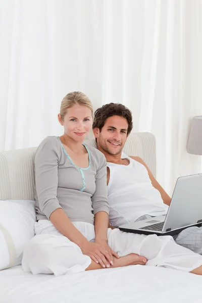 Entzückendes Paar schaut auf seinen Laptop auf dem Bett — Stockfoto