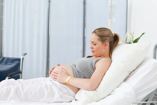 Беременная девушка на больничной койке — стоковое фото