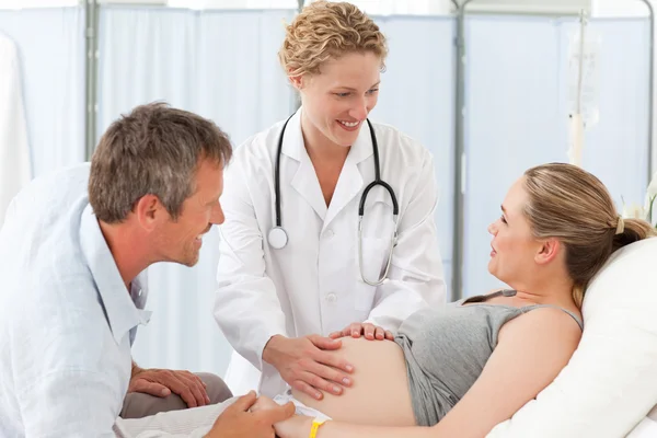 Zwangere vrouw met haar echtgenoot luisteren naar de verpleegkundige — Stockfoto