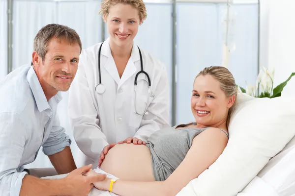 Беременная женщина с мужем и медсестрой, смотрящей на камеру — стоковое фото