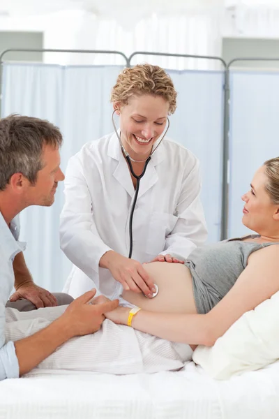Беременная женщина с мужем слушает медсестру — стоковое фото
