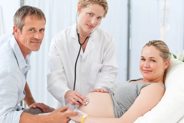 Mulher grávida com o marido e a enfermeira olhando para a cam — Fotografia de Stock