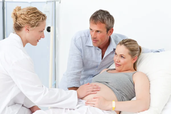 Zwangere vrouw met haar echtgenoot luisteren naar de verpleegkundige — Stockfoto