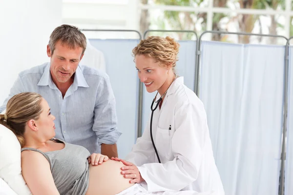 Беременная женщина с мужем слушает медсестру — стоковое фото