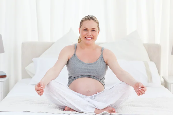 Беременная женщина практикует йогу на кровати — стоковое фото