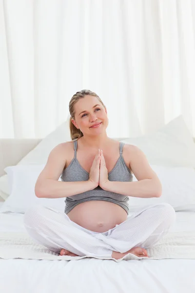Těhotná žena cvičí jógu na posteli — Stock fotografie