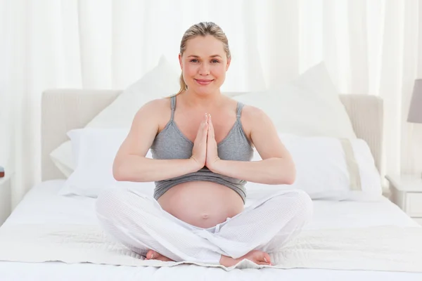妊娠中の女性が彼女のベッドにヨガの練習 — ストック写真