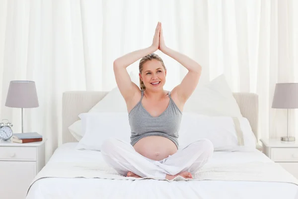 Mulher grávida praticando ioga em sua cama — Fotografia de Stock
