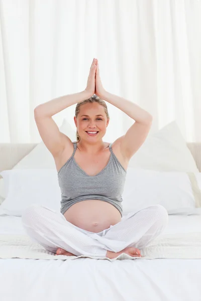 Pregnant woman practicing yoga on her bed — Stock Photo, Image