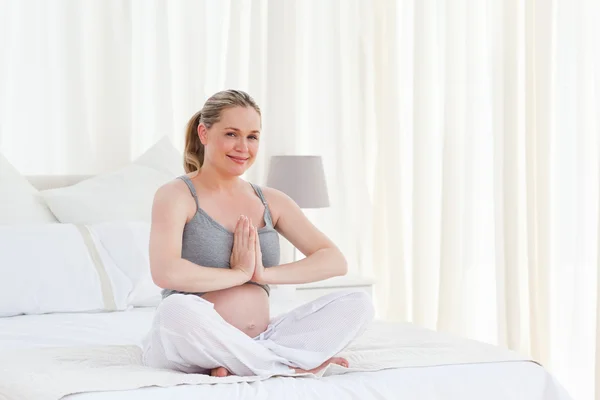 Беременная женщина практикует йогу на кровати — стоковое фото