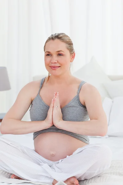 Mujer embarazada practicando yoga en su cama — Foto de Stock