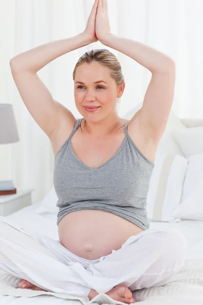 Mulher grávida praticando ioga em sua cama — Fotografia de Stock
