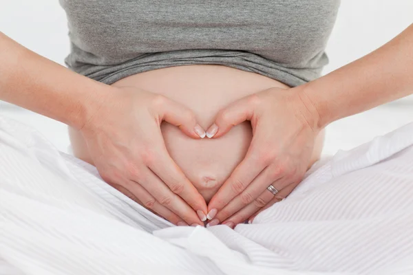 Pregnant woman doing heart sign on her belly — Stock Photo, Image