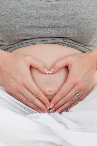 임신한 여 자가 그녀의 배꼽에 하트 표시를 하 고 — 스톡 사진