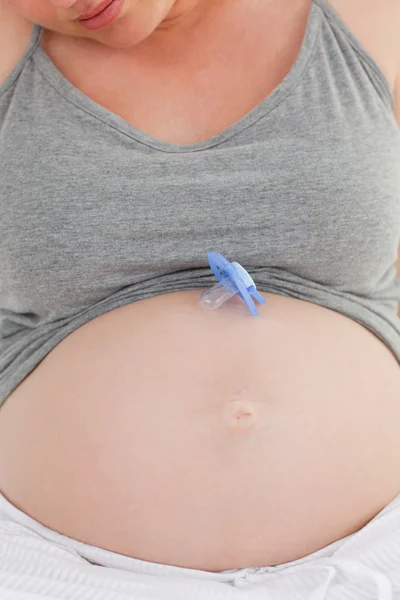 Mulher grávida com um boneco de bebê na barriga em casa — Fotografia de Stock