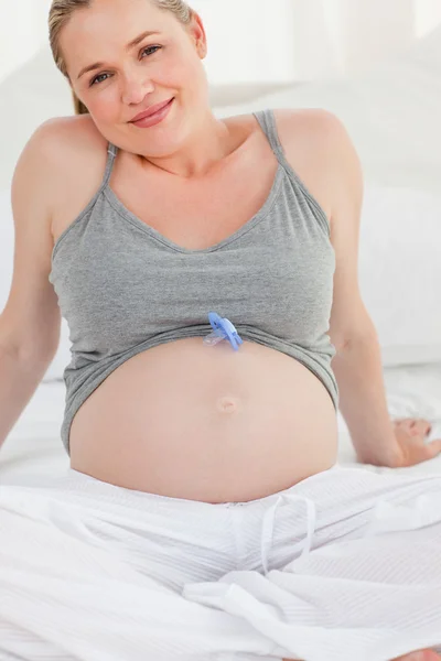 Mulher grávida com um boneco de bebê na barriga em casa — Fotografia de Stock