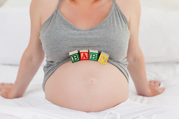 Беременная женщина с кубиками на животе — стоковое фото
