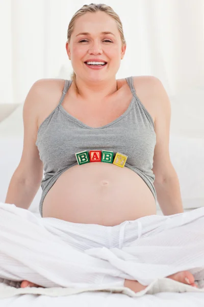 Těhotná žena s baby kostky na břiše — Stock fotografie