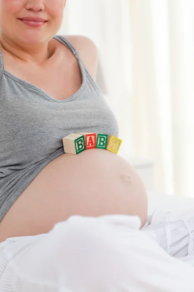 Zwangere vrouw met baby kubussen op haar buik — Stockfoto