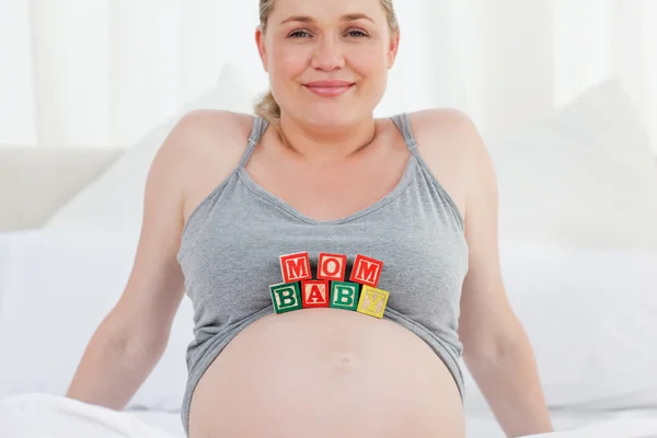 Těhotná žena s baby kostky na břiše — Stock fotografie