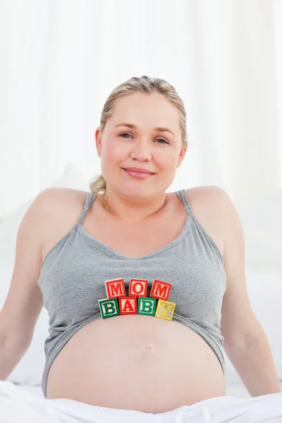 Беременная женщина с кубиками на животе — стоковое фото
