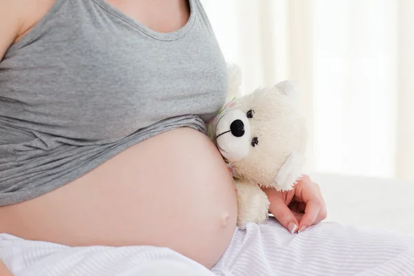 Беременная женщина с мягкой игрушкой — стоковое фото