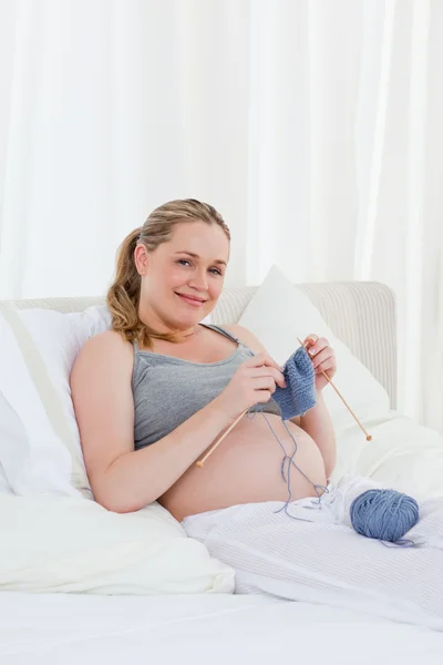 Adorabile donna incinta a maglia sul suo letto — Foto Stock