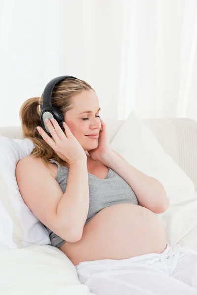 아름 다운 임신한 여자는 그녀의 침대에서 음악을 듣고 — 스톡 사진