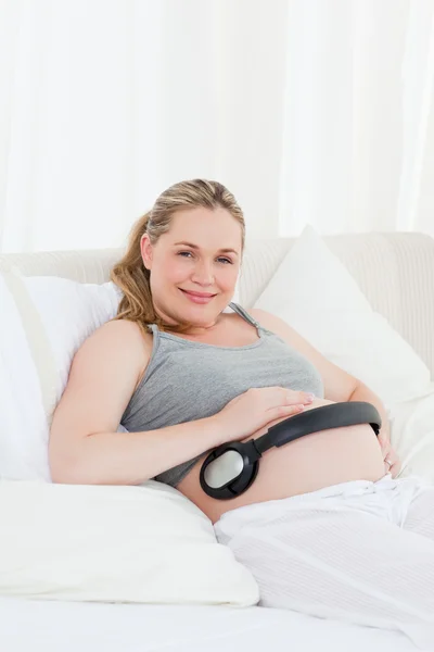 Kobieta w ciąży oddanie jej słuchawki na brzuchu — Zdjęcie stockowe