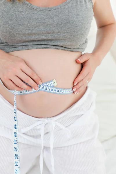 Närbild av en kvinna som mäter hennes mage — Stockfoto
