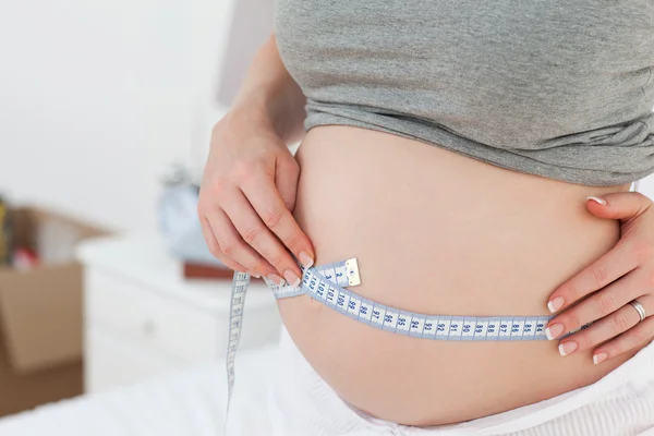 Närbild av en kvinna som mäter hennes mage — Stockfoto