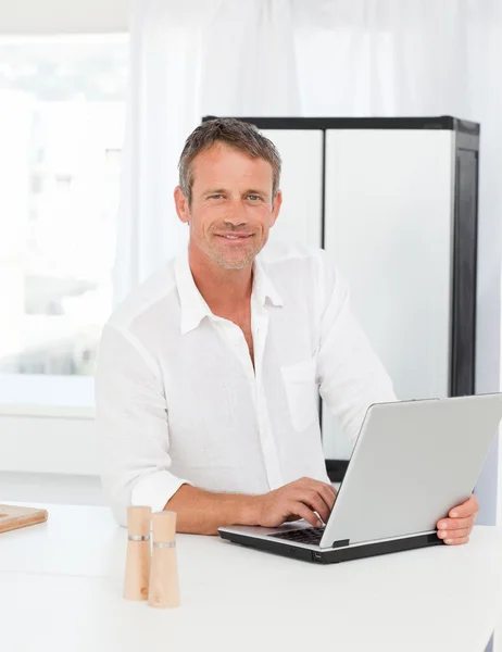 Homem trabalhando em seu laptop em sua cozinha — Fotografia de Stock