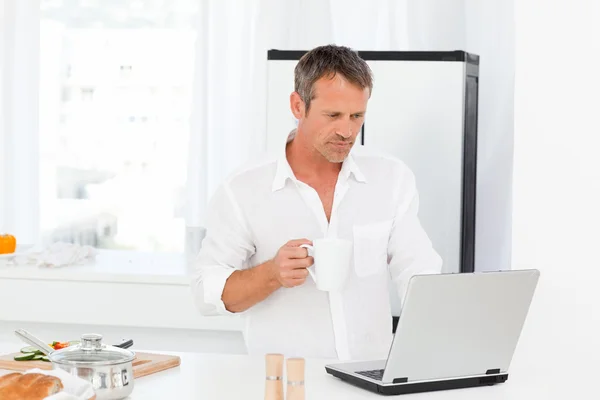 Homem olhando para seu laptop enquanto ele está bebendo — Fotografia de Stock