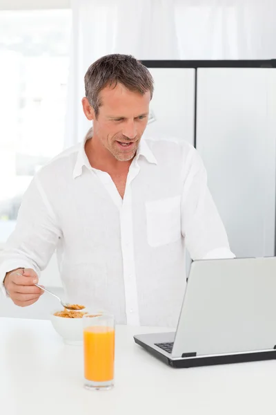 彼は彼のラップトップに取り組んでいる間食べている男の穀物 — ストック写真