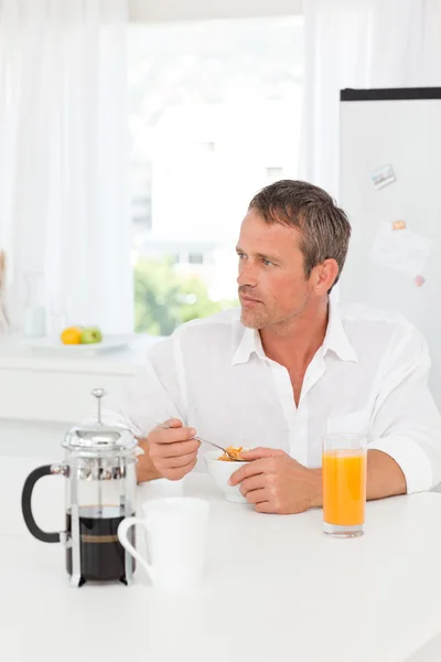 Bonito homem tomando seu café da manhã na cozinha — Fotografia de Stock