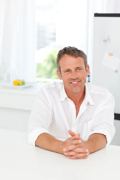 Handsome man sitting in his kitchen — Stock Photo, Image