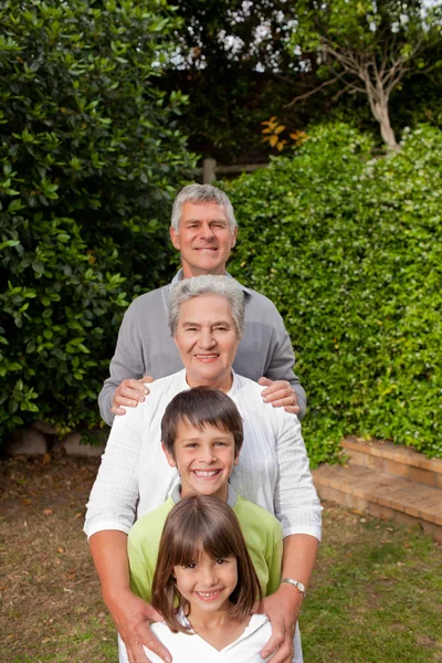 Prarodiče s vnoučaty, při pohledu na fotoaparát — Stock fotografie