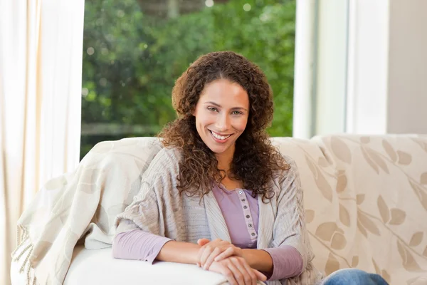 Usmívající se žena sedí na jejím gauči — Stock fotografie