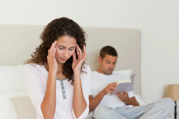 彼女の夫が読んでいる間に、頭痛を持つ女性 — ストック写真