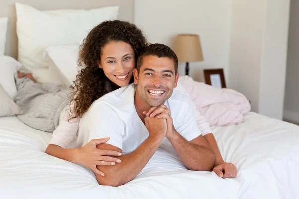 Hübsche Frau umarmt ihren Mann auf ihrem Bett zu Hause — Stockfoto