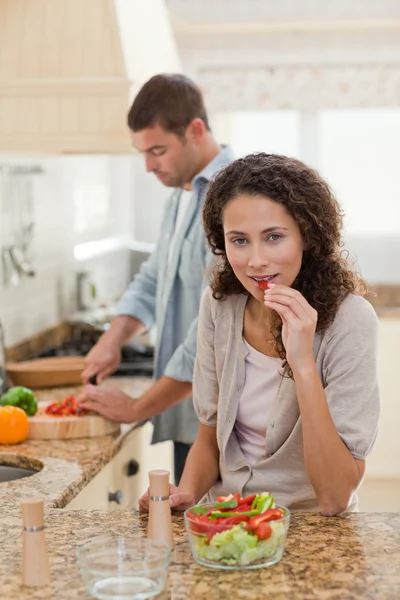 Kvinna äter medan hennes man är matlagning — Stockfoto