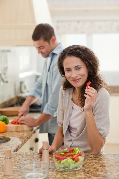 Kobieta jedzenie, podczas gdy jej mąż gotuje — Zdjęcie stockowe